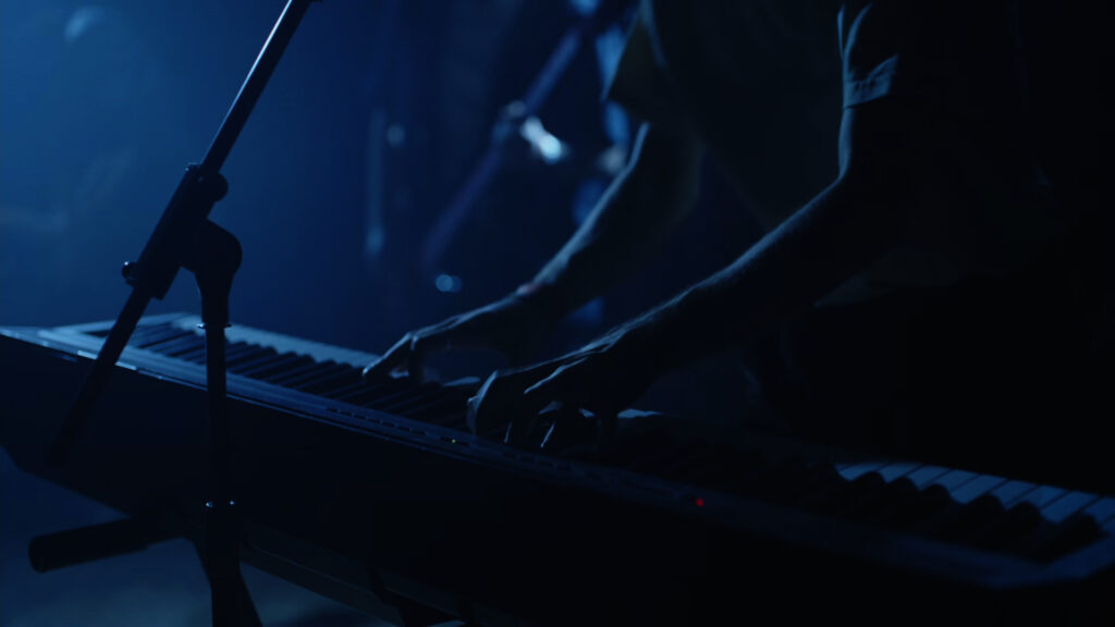 Le chanteur et musicien Thomas du groupe Alabel au clavier en plan serré lors d'une prestation de concert filmé en multicaméras par la Mine productions