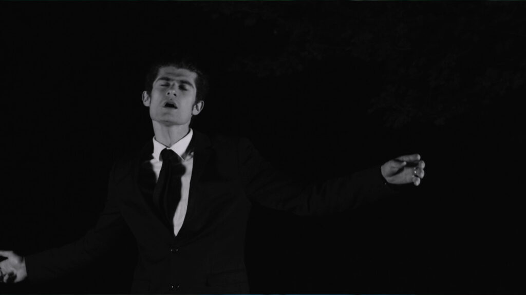 Kirkor Albert interprétant son titre "les mots" lors du tournage du clp réalisé par la Mine Productions. Ici Albert est de face en plan taille en noir et blanc dans la nuit.